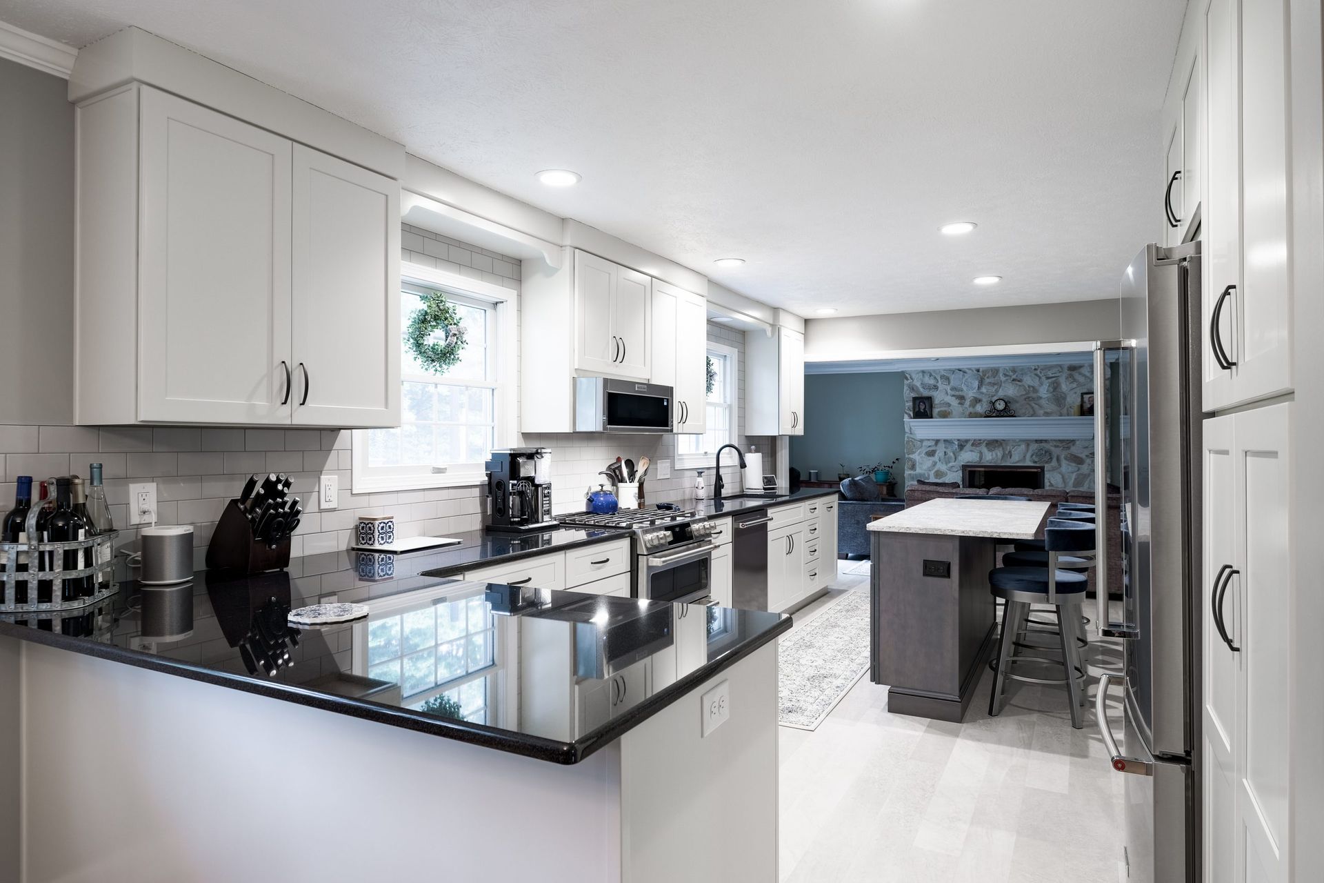 A kitchen with white cabinets and black granite counter tops.