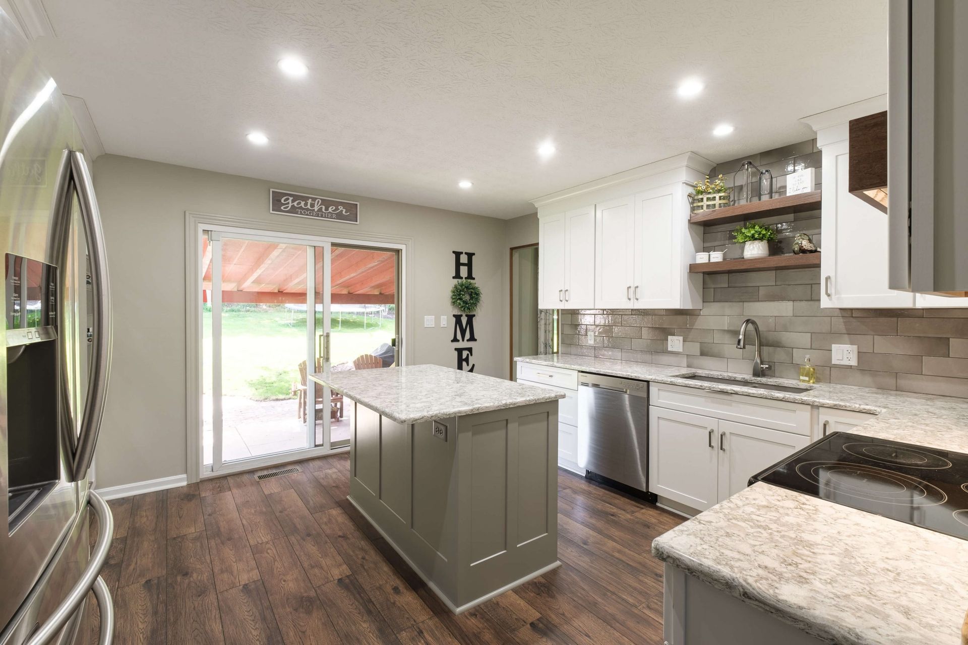 A kitchen with white cabinets , granite counter tops , stainless steel appliances and a large island.