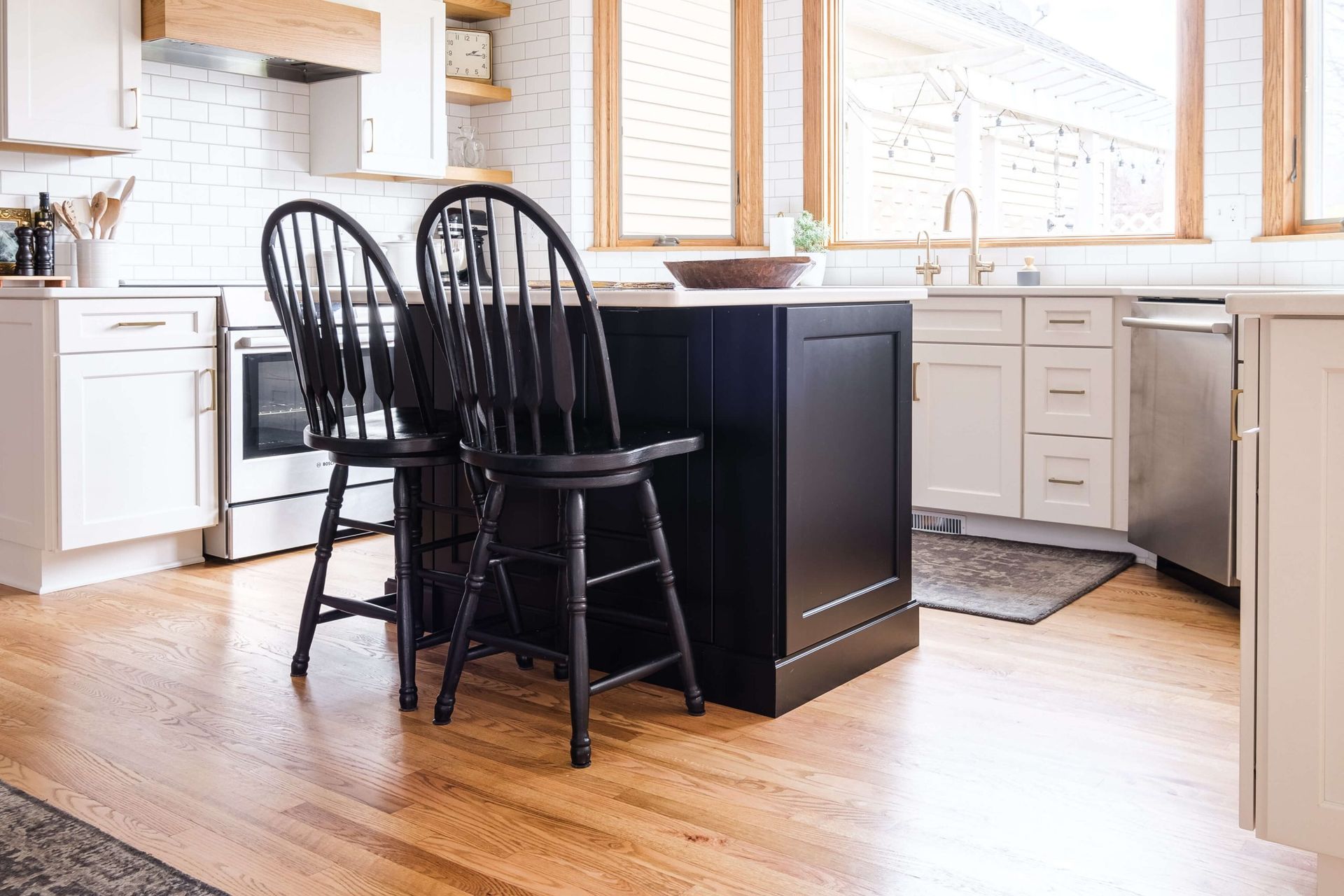 A kitchen with a black island and two chairs.