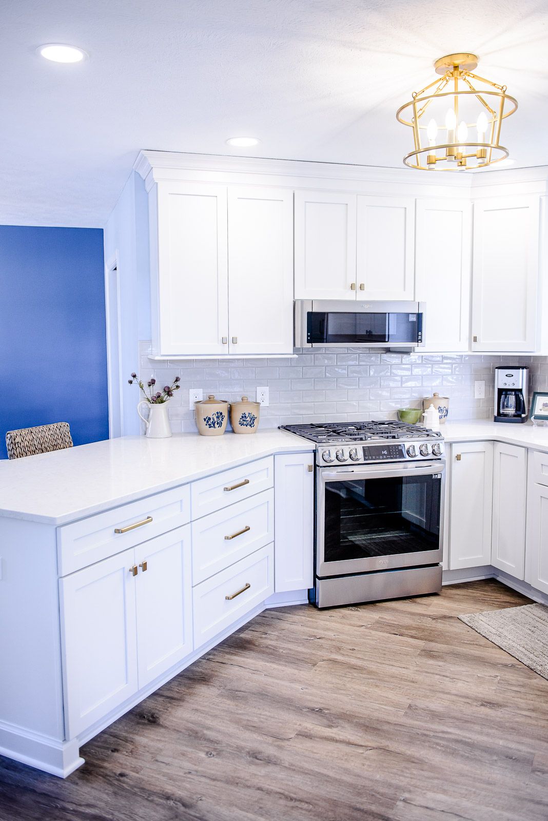 A kitchen with white cabinets , a stove , a microwave , and a coffee maker.
