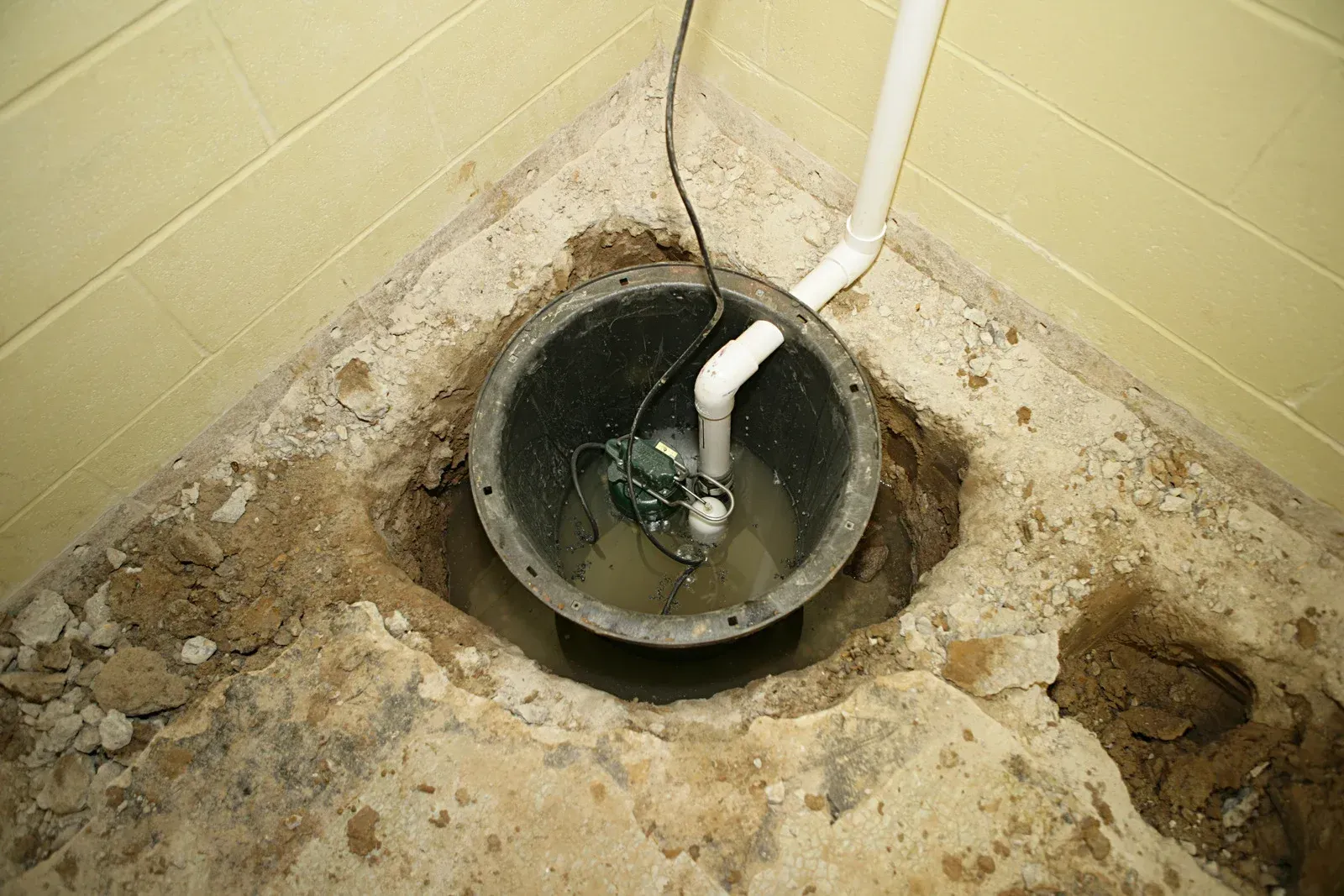 A sump pump is being installed in a basement.