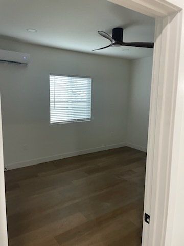 An empty bedroom with a ceiling fan and a window.