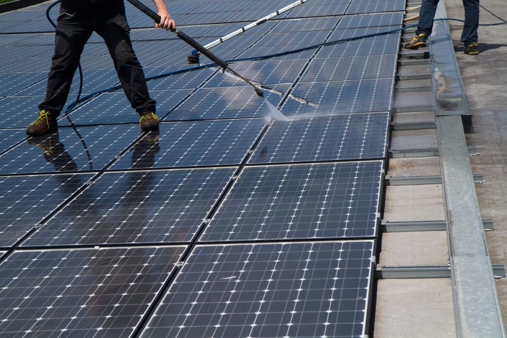 Person Washing Solar Panels on a Roof With a Pressure Washer — LSEA Electrical Group in Bucasia, QLD
