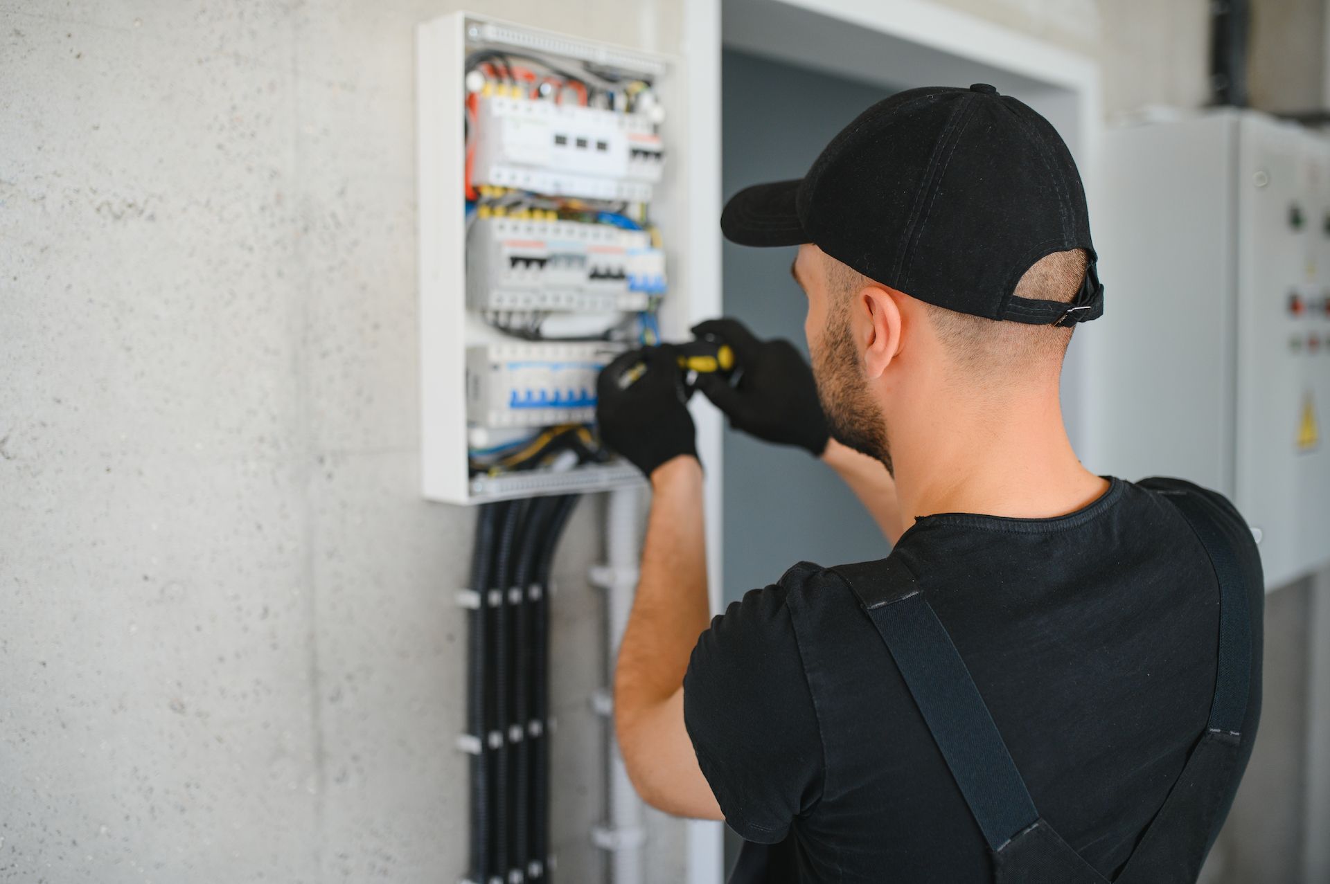 Electrician in Black Cap and Gloves, Working on a Circuit Breaker Box — LSEA Electrical Group in Nebo, QLD
