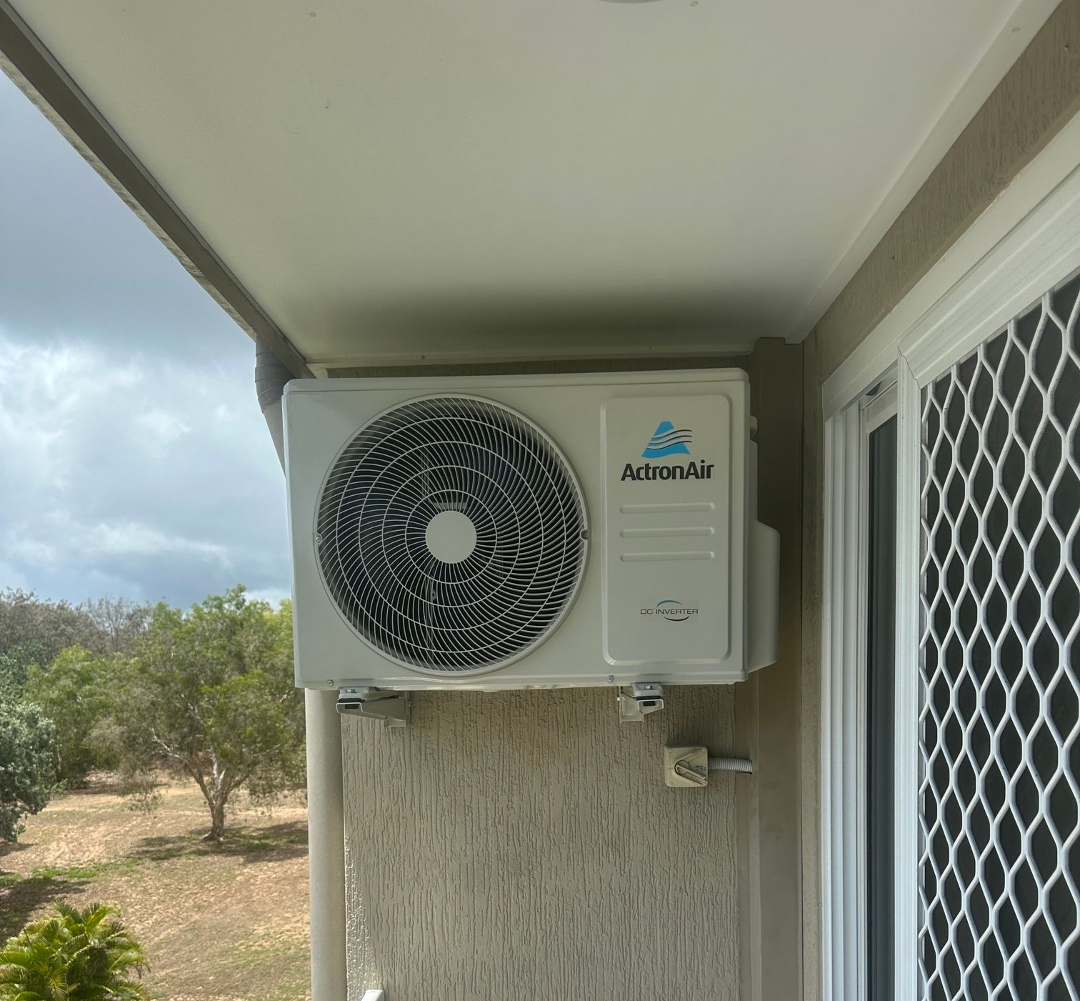 An Arlec Air Air Conditioning Unit Mounted on an Exterior Wall Next to a Screen Door — LSEA Electrical Group in Bucasia, QLD