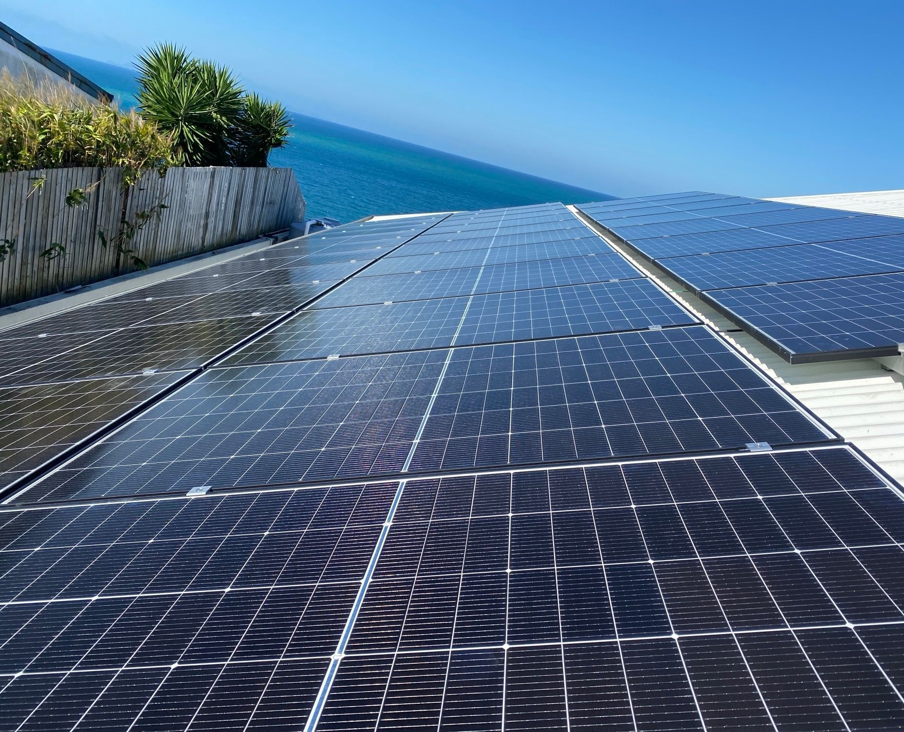 Workers in Blue Coveralls Install Solar Panels on a Metal Frame, Outdoors — LSEA Electrical Group in Bucasia, QLD