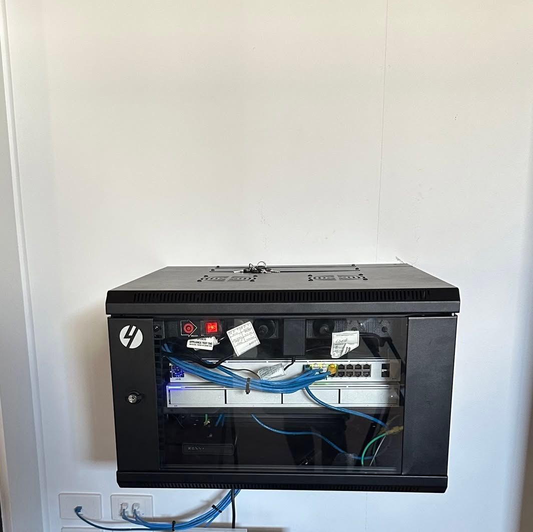 Open Wall-mounted Black Network Cabinet With Visible Blue Cables and Equipment — LSEA Electrical Group in Bucasia, QLD