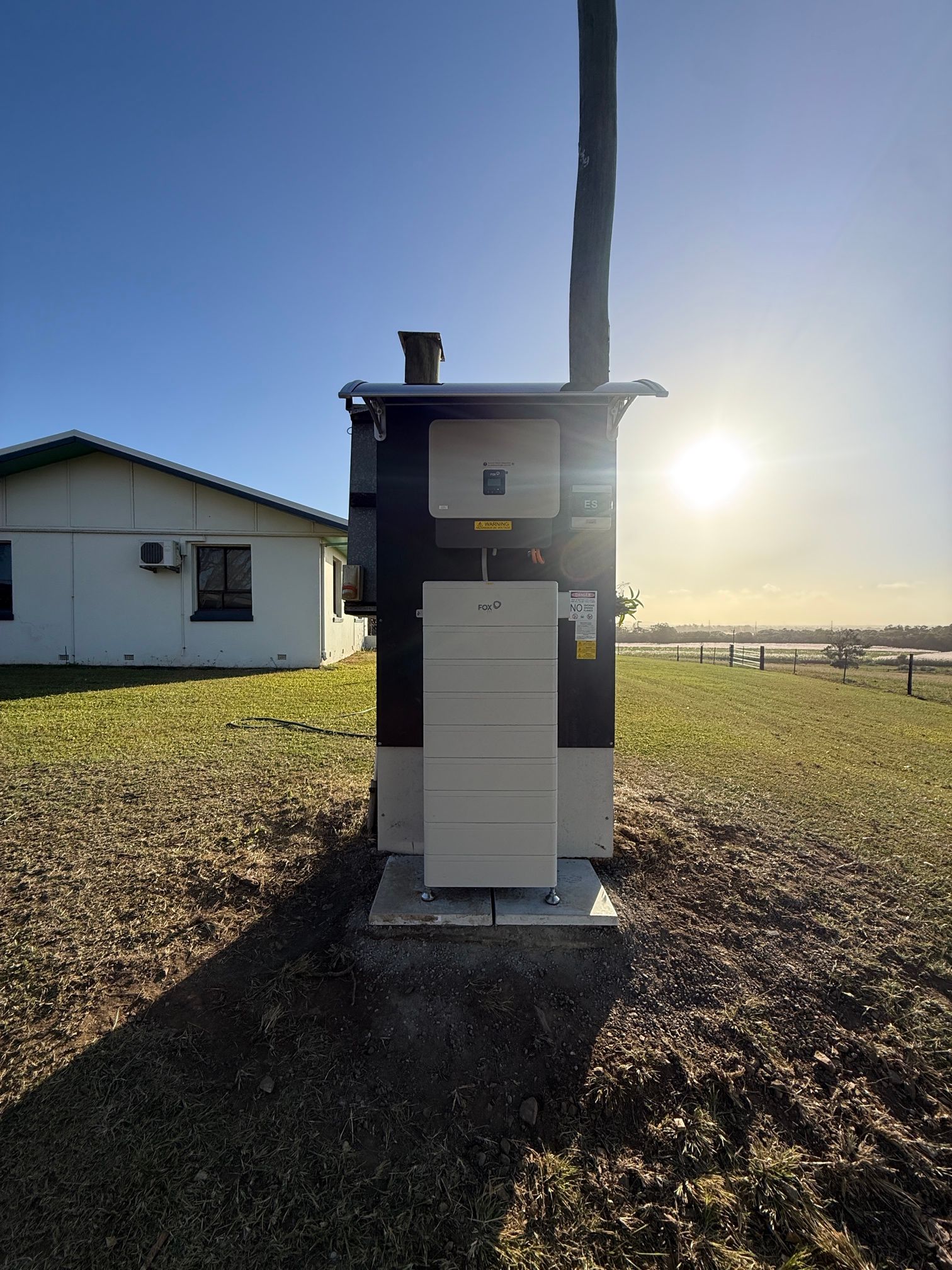 Outdoor utility meter cabinet beside a house at sunrise, with fields in the background — LSEA Electrical Group in Bucasia, QLD