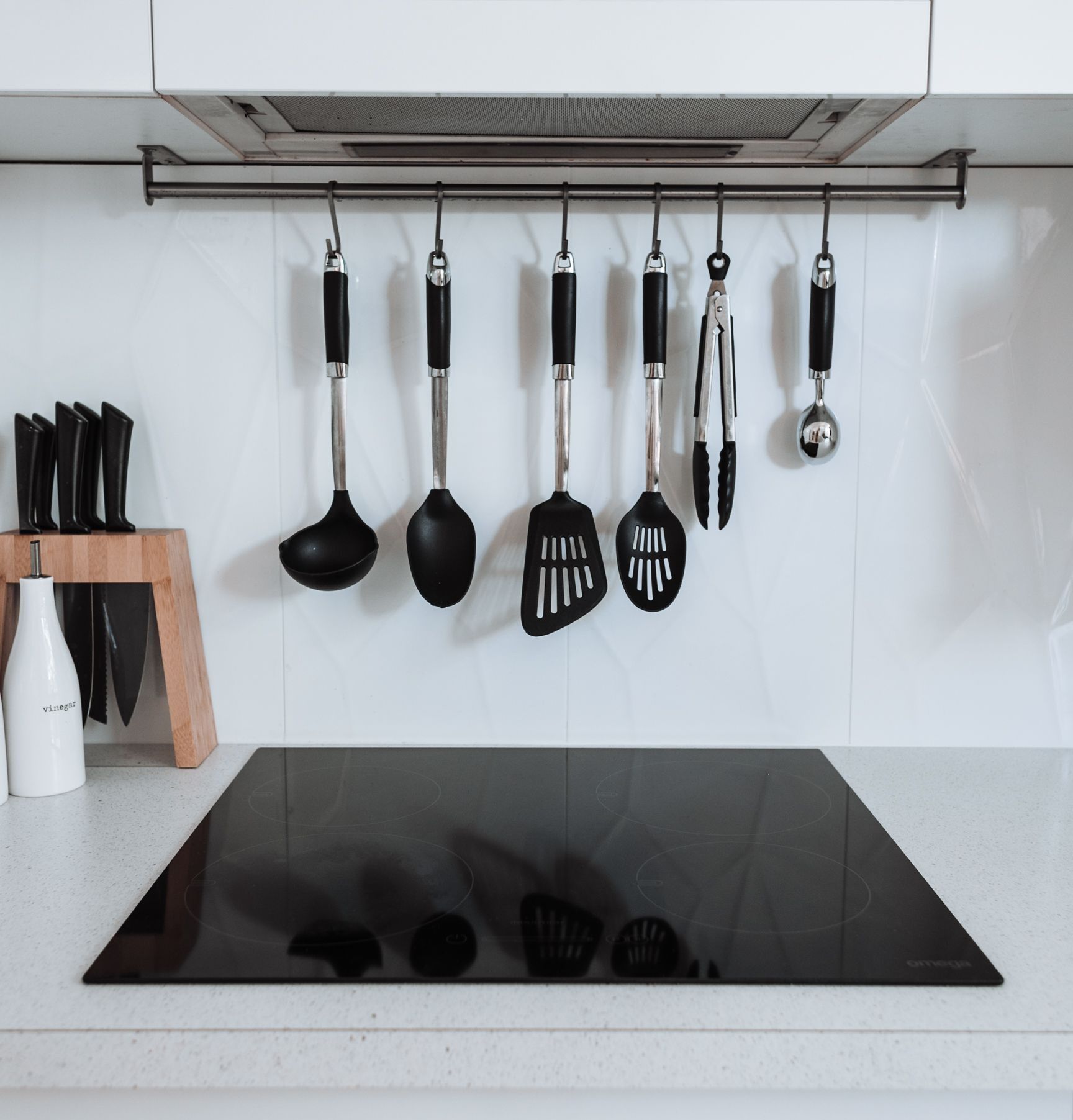 Modern kitchen with black cooktop and hanging black utensils on a rack above the counter  — LSEA Electrical Group in Bucasia, QLD