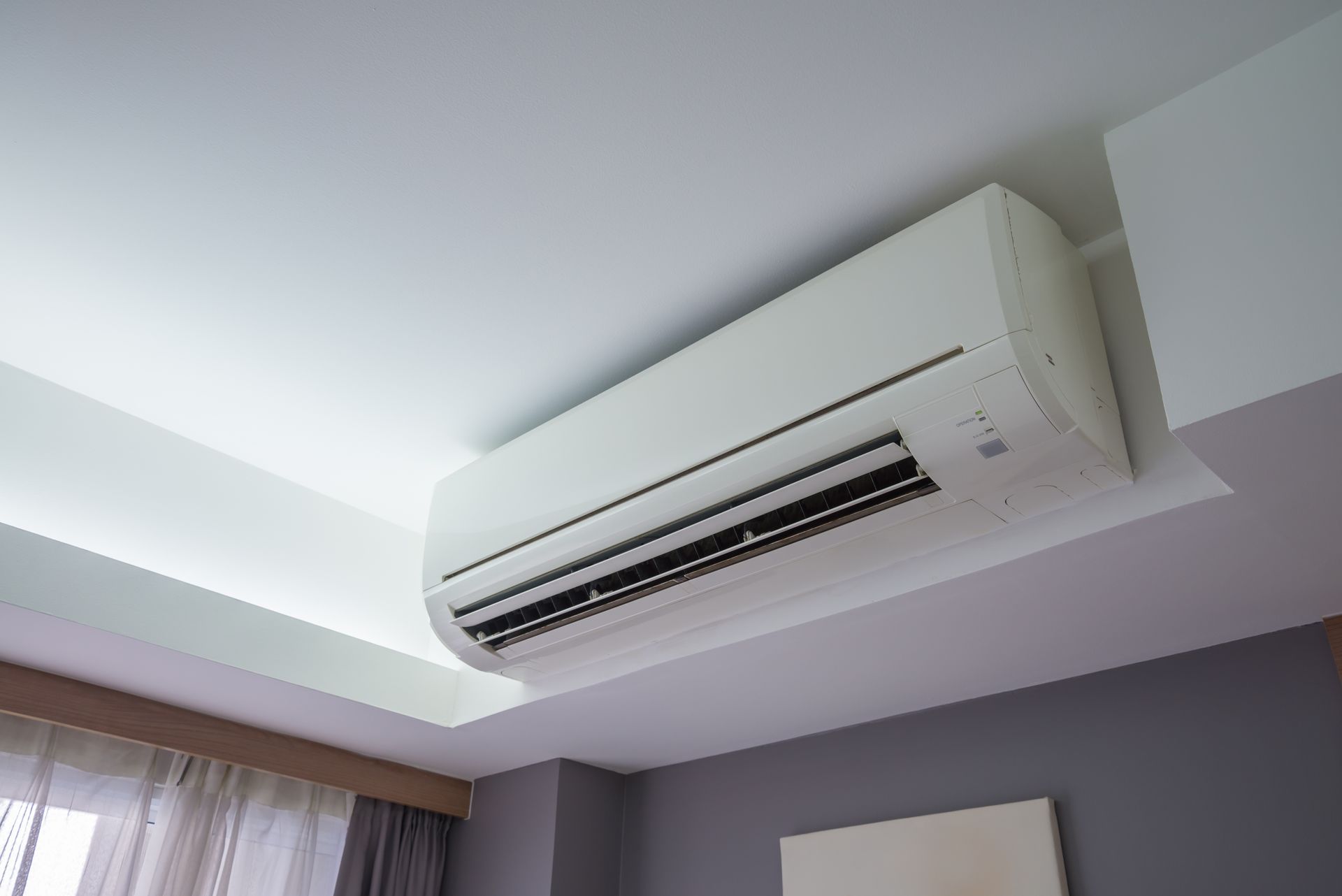 White Wall-mounted Air Conditioner On A White Ceiling In A Gray-walled Room— LSEA Electrical Group in Bucasia, QLD
