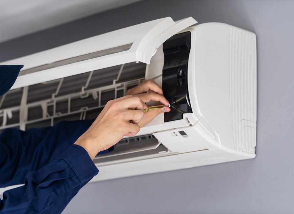 Technician Cleaning a Wall-mounted Air Conditioner — LSEA Electrical Group in Bucasia, QLD