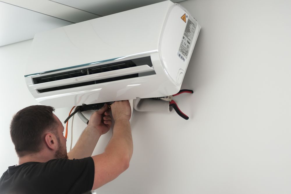 Technician Installing a Wall-mounted Air Conditioner — LSEA Electrical Group in Bucasia, QLD