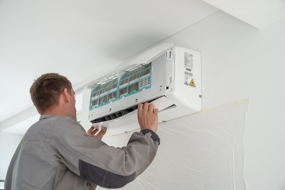 Technician Installing a Aircon on White Wall — LSEA Electrical Group in Bucasia, QLD