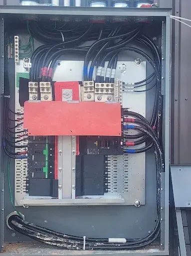 Open electrical control panel with wiring, circuit breakers, and red cover