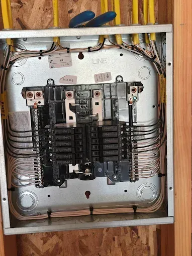Open electrical breaker panel with wiring, switches, and a metal enclosure.