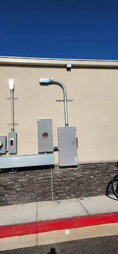 Outdoor beige building wall with utility boxes, pipes, and a red curb in front.