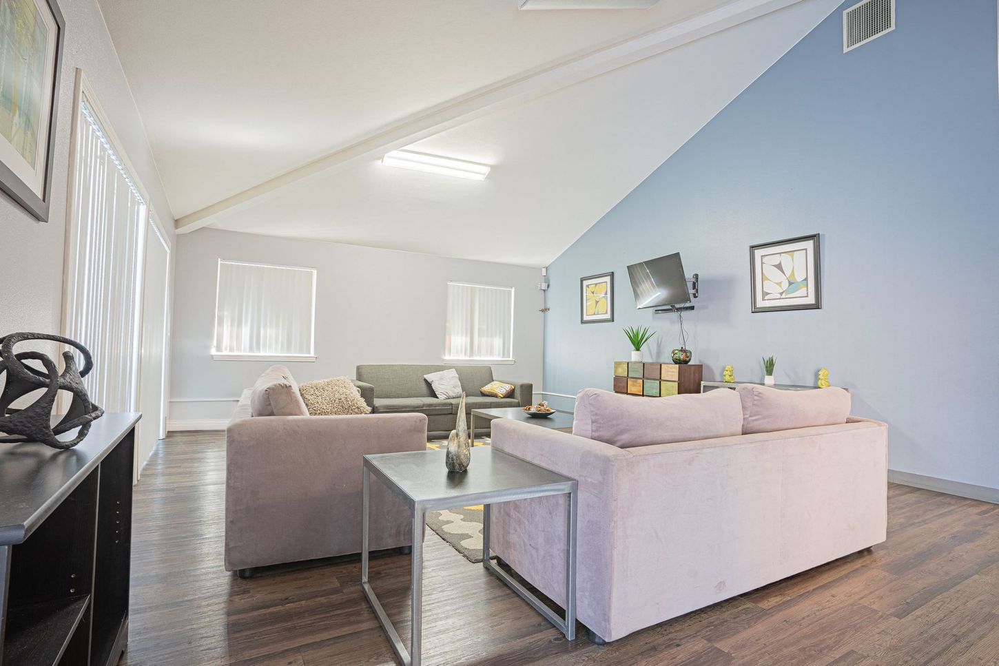 Living room with blue and white walls, two pink sofas, and a gray couch.