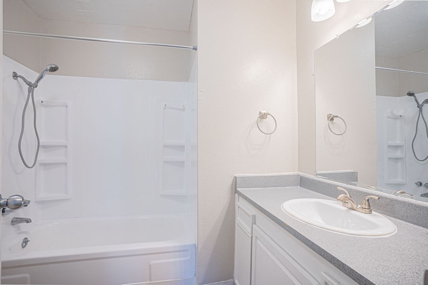 Bathroom with white fixtures, shower/tub combo, vanity, and mirror.