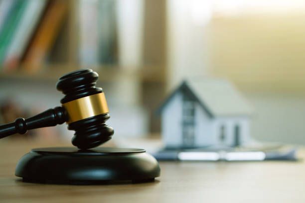 A judge 's gavel is sitting on a wooden table in front of a model house.