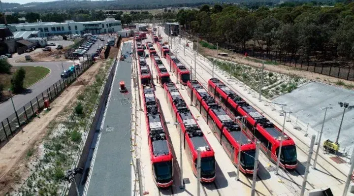 A bunch of red trains are parked on the tracks.