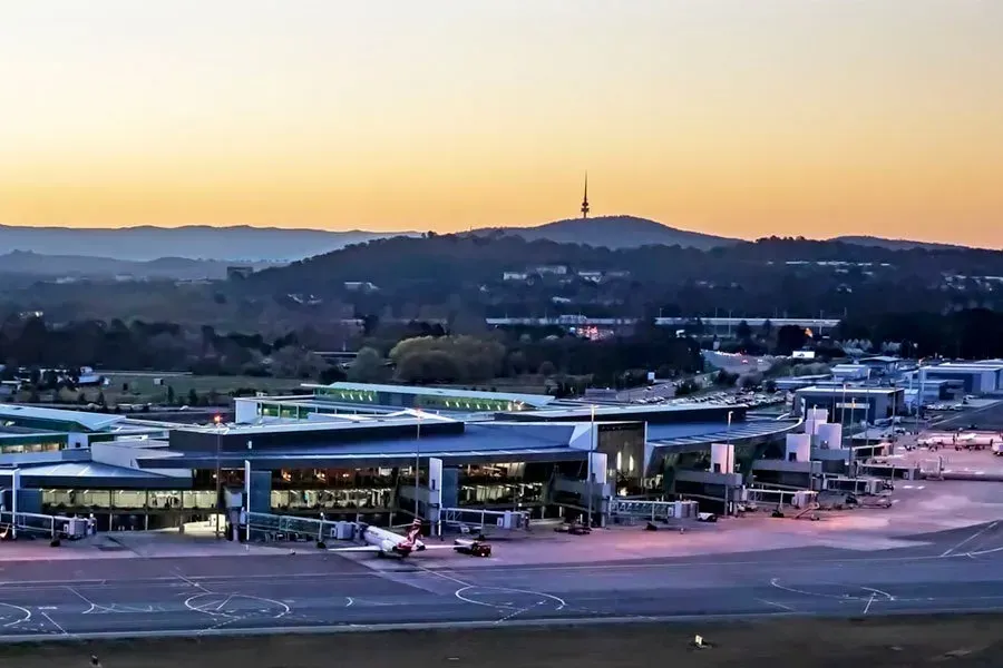 An aerial view of an airport at sunset with mountains in the background