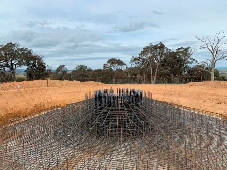 A large metal structure is sitting in the middle of a dirt field.