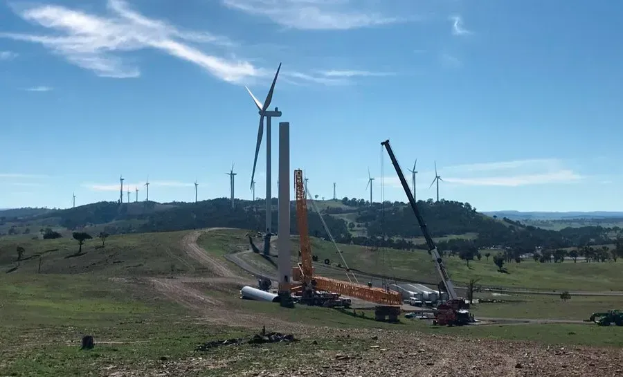 A group of wind turbines are being built in a field.