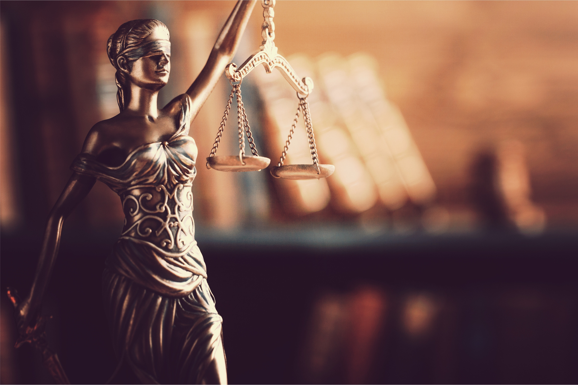 Lady Justice statue with scales of balance in courtroom symbolizing law.