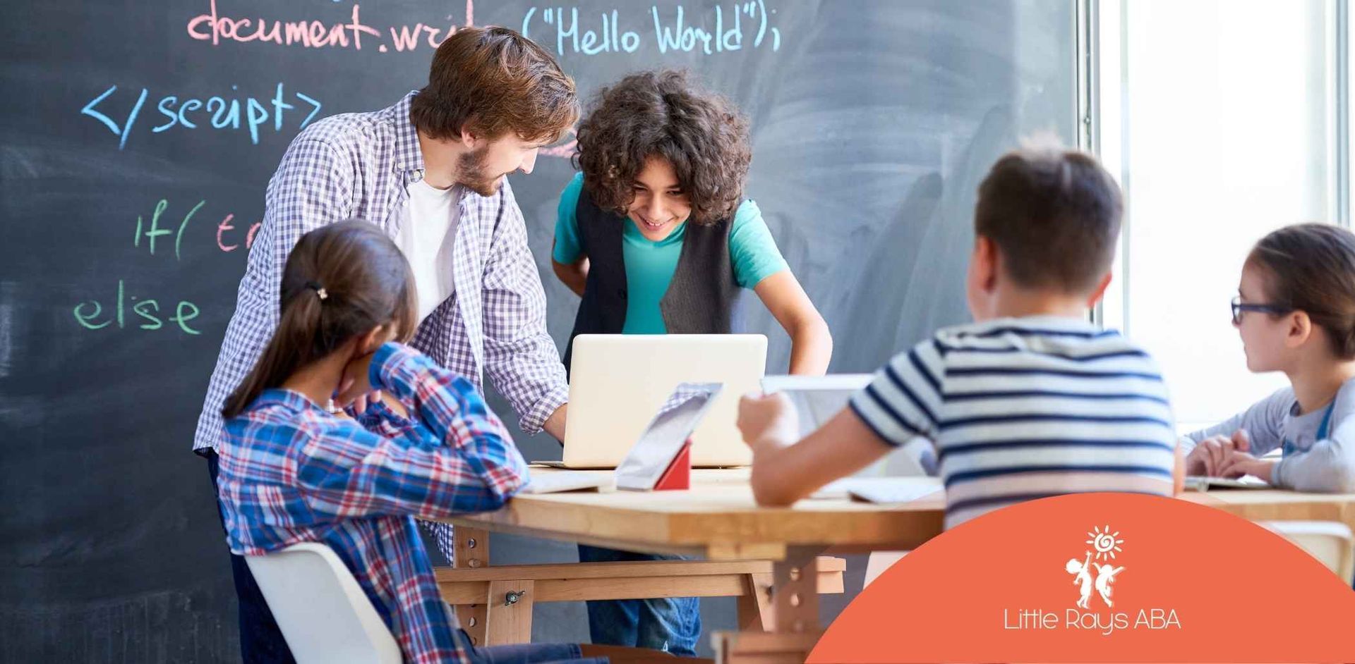 Teacher and students coding on a laptop in a classroom; chalkboard background.