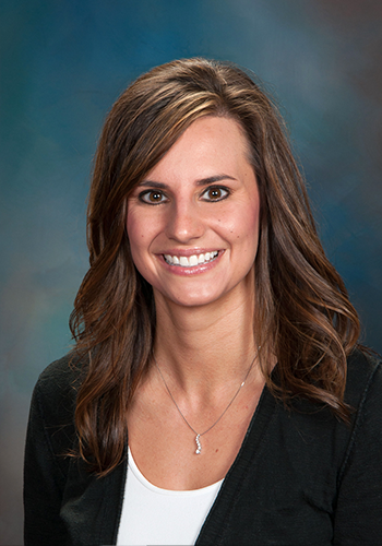 A woman wearing a black jacket and a white shirt is smiling for the camera.
