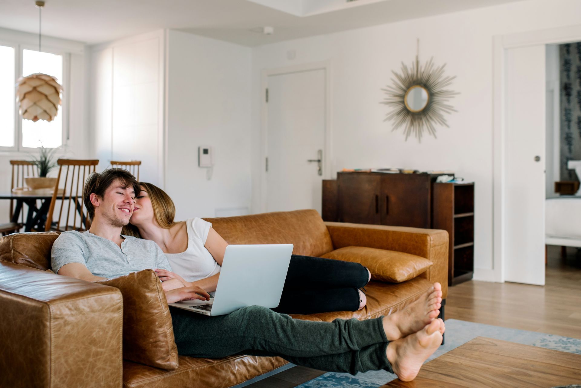 A man and a woman are sitting on a couch with a laptop.