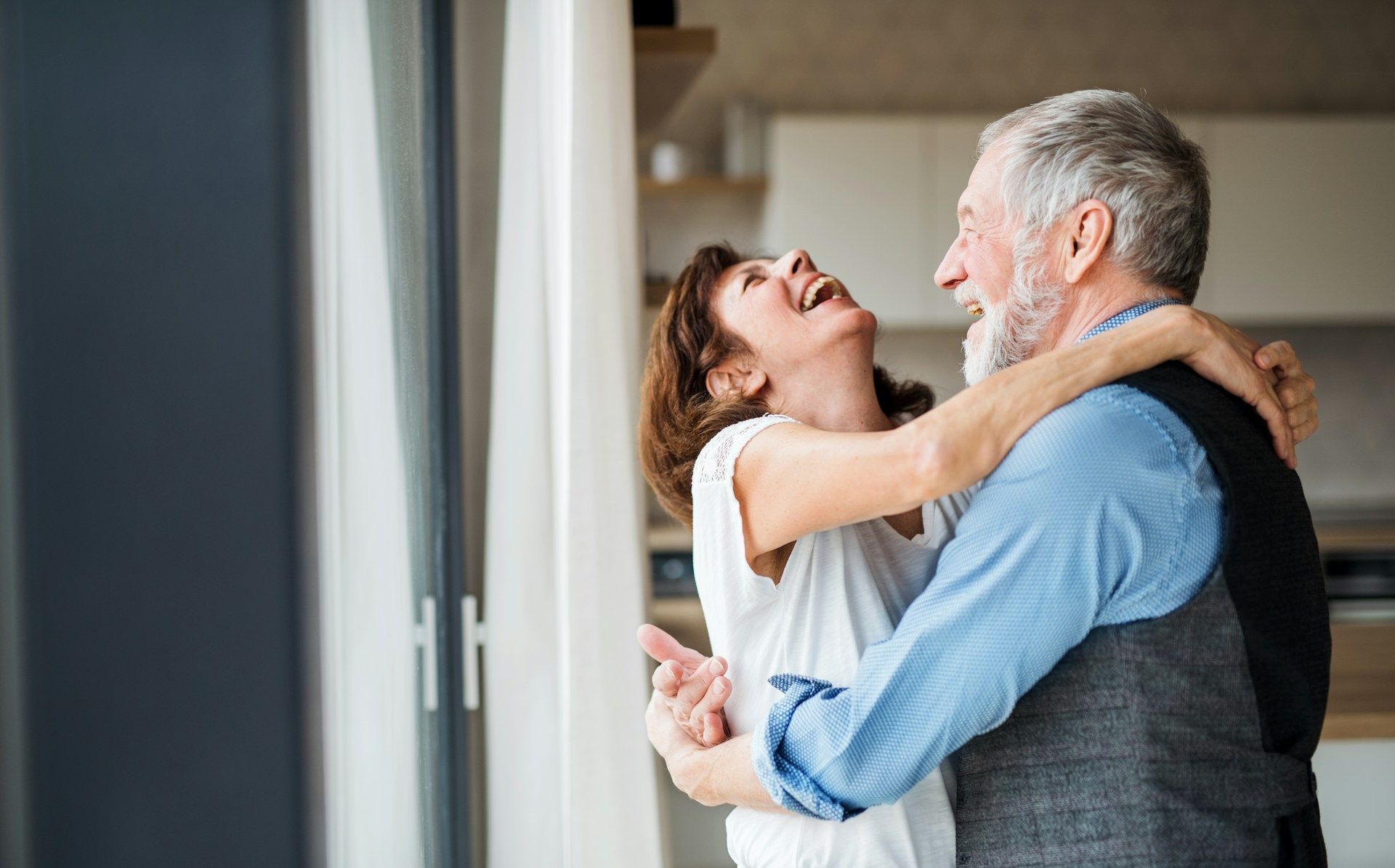 A man and a woman are dancing in front of a window.