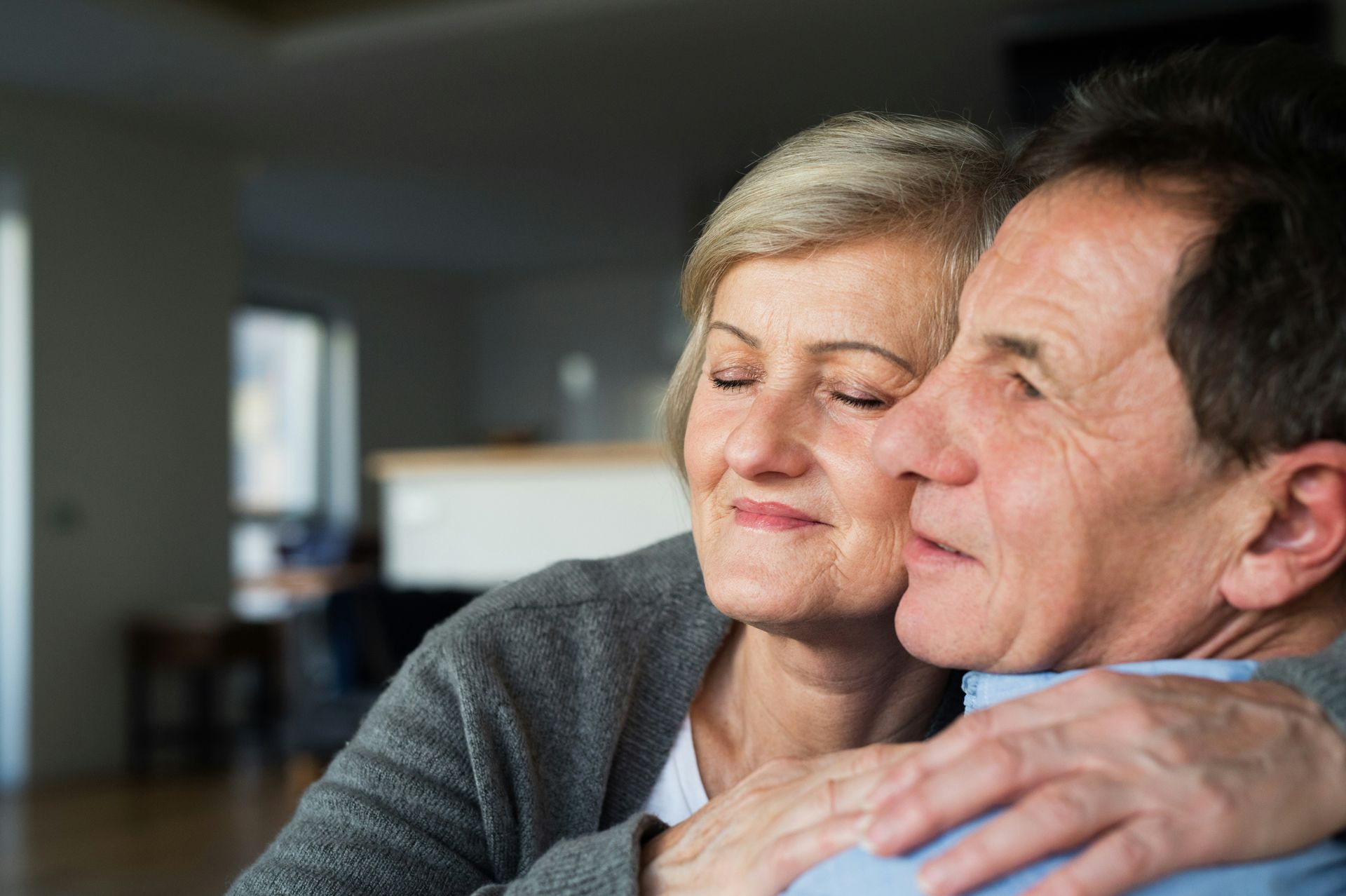 A man and a woman are hugging each other in a living room.