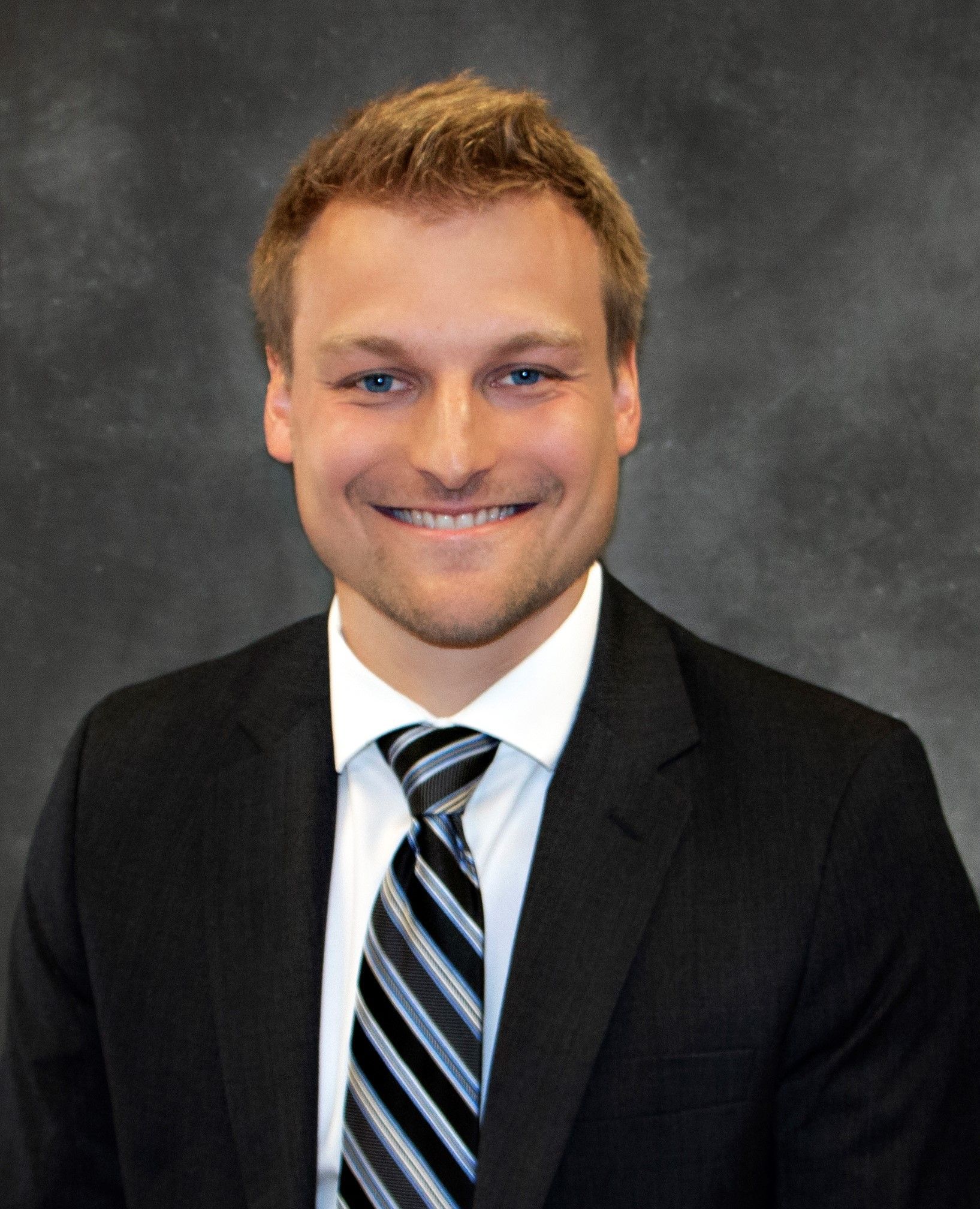A man in a suit and tie is smiling for the camera