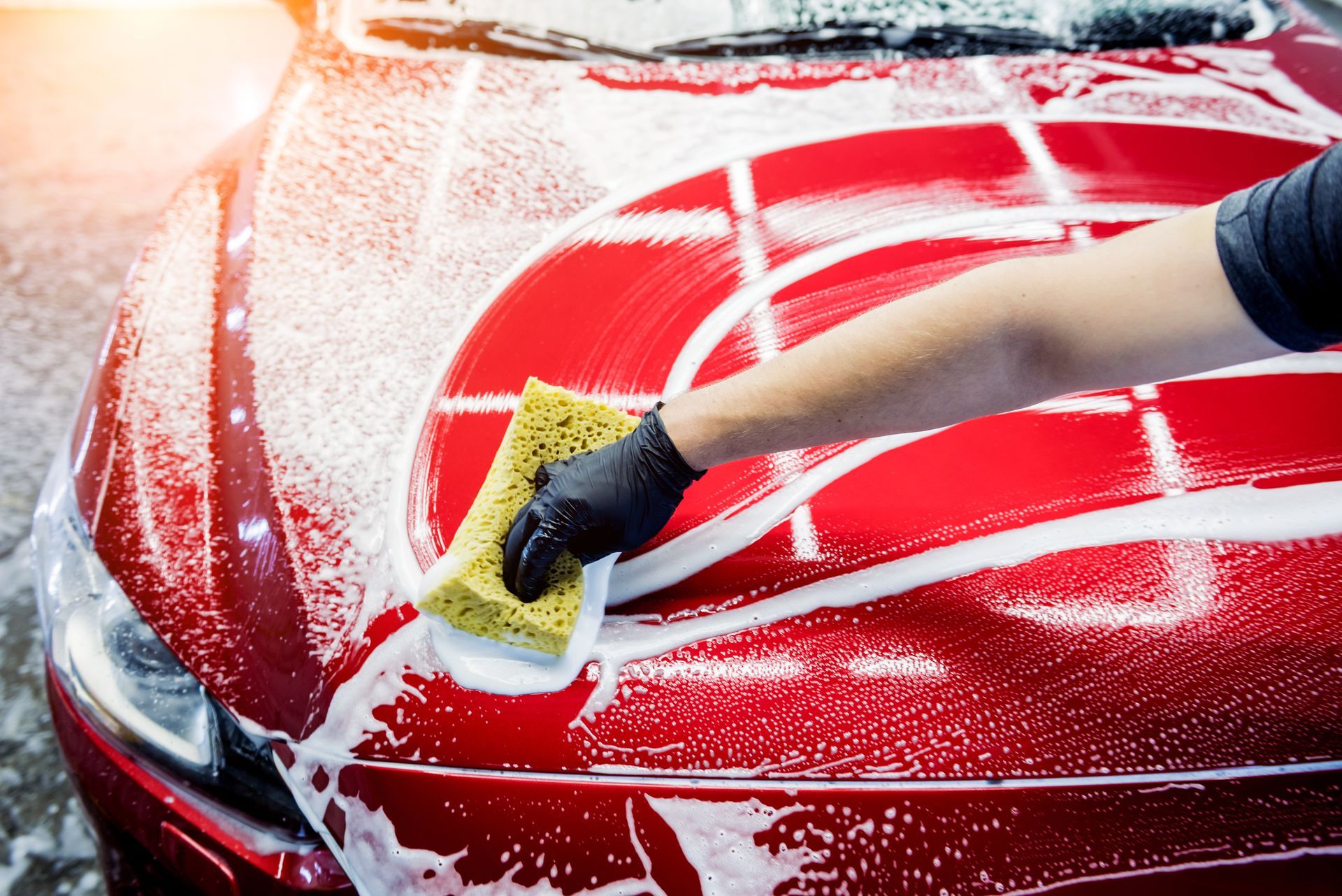 A Person Is Washing A Red Car With A Sponge - San Pablo, CA - Grand Prix Car Wash San Pablo