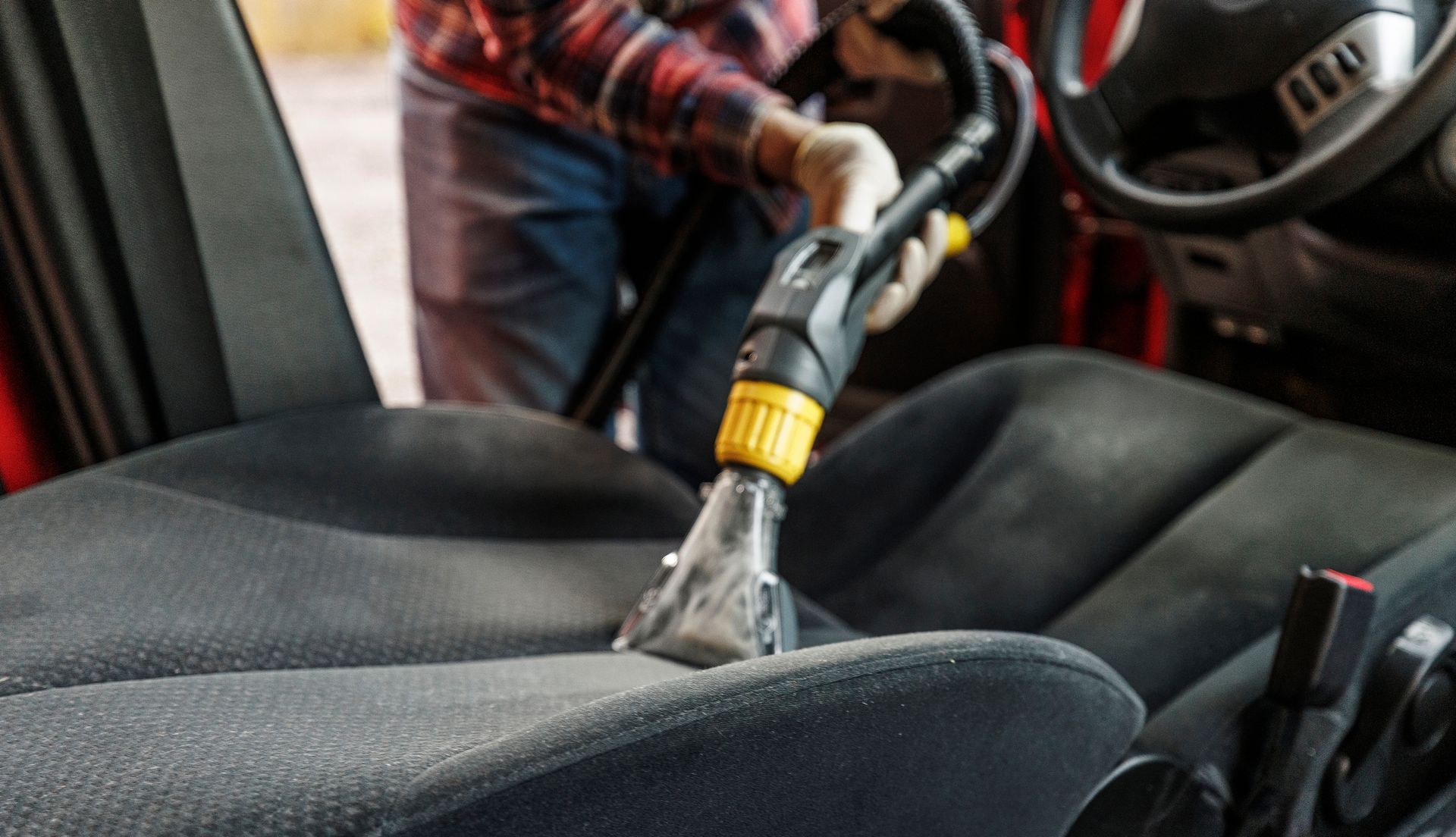 A Man Is Cleaning The Seats Of A Car With A Vacuum Cleaner - San Pablo, CA - Grand Prix Car Wash San Pablo