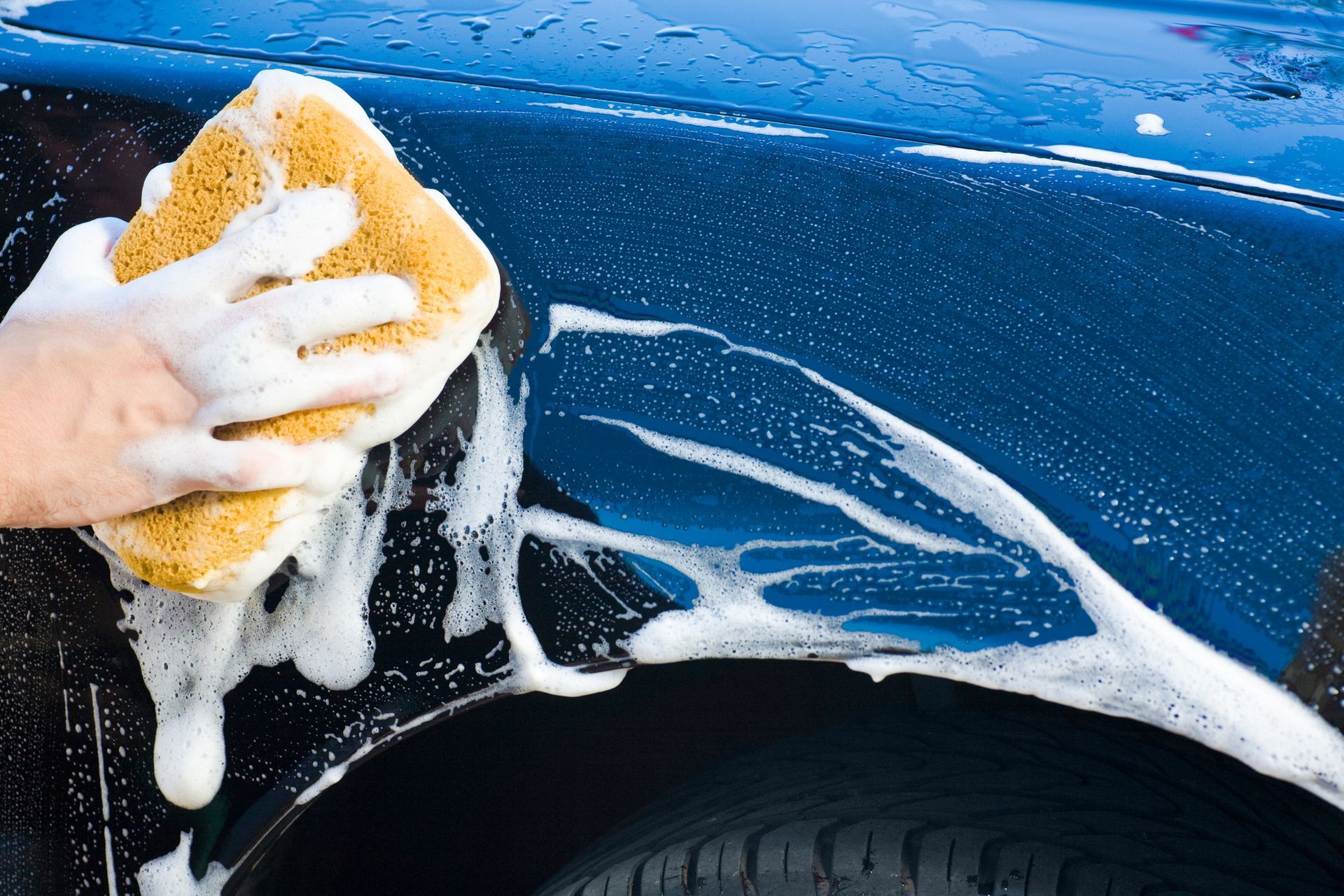 A Person Is Washing A Blue Car With A Sponge - San Pablo, CA - Grand Prix Car Wash San Pablo