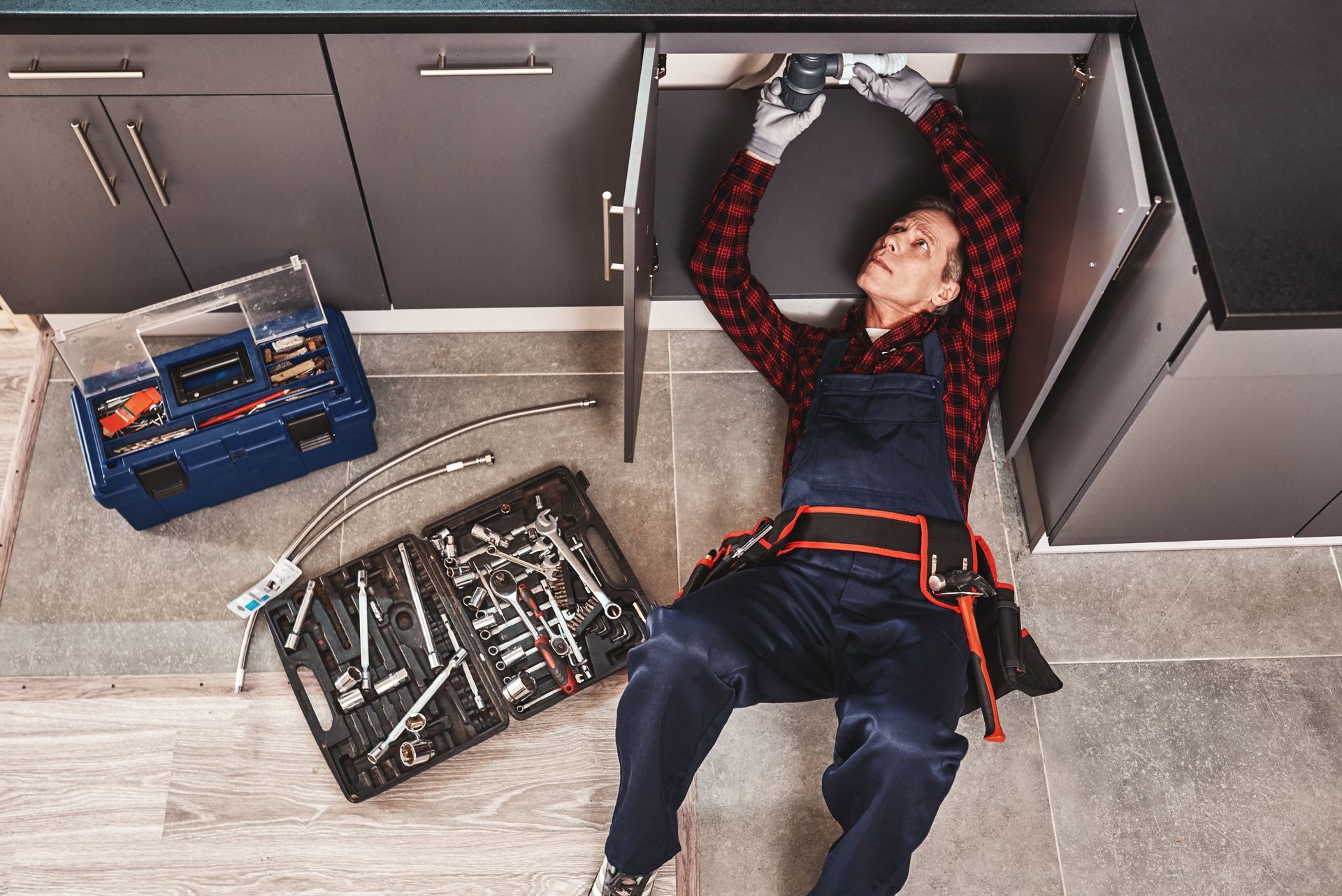 A man is working under a kitchen sink.