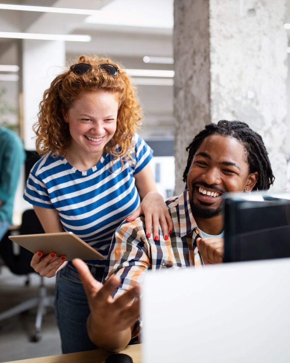 A man and a woman are looking at a laptop computer.