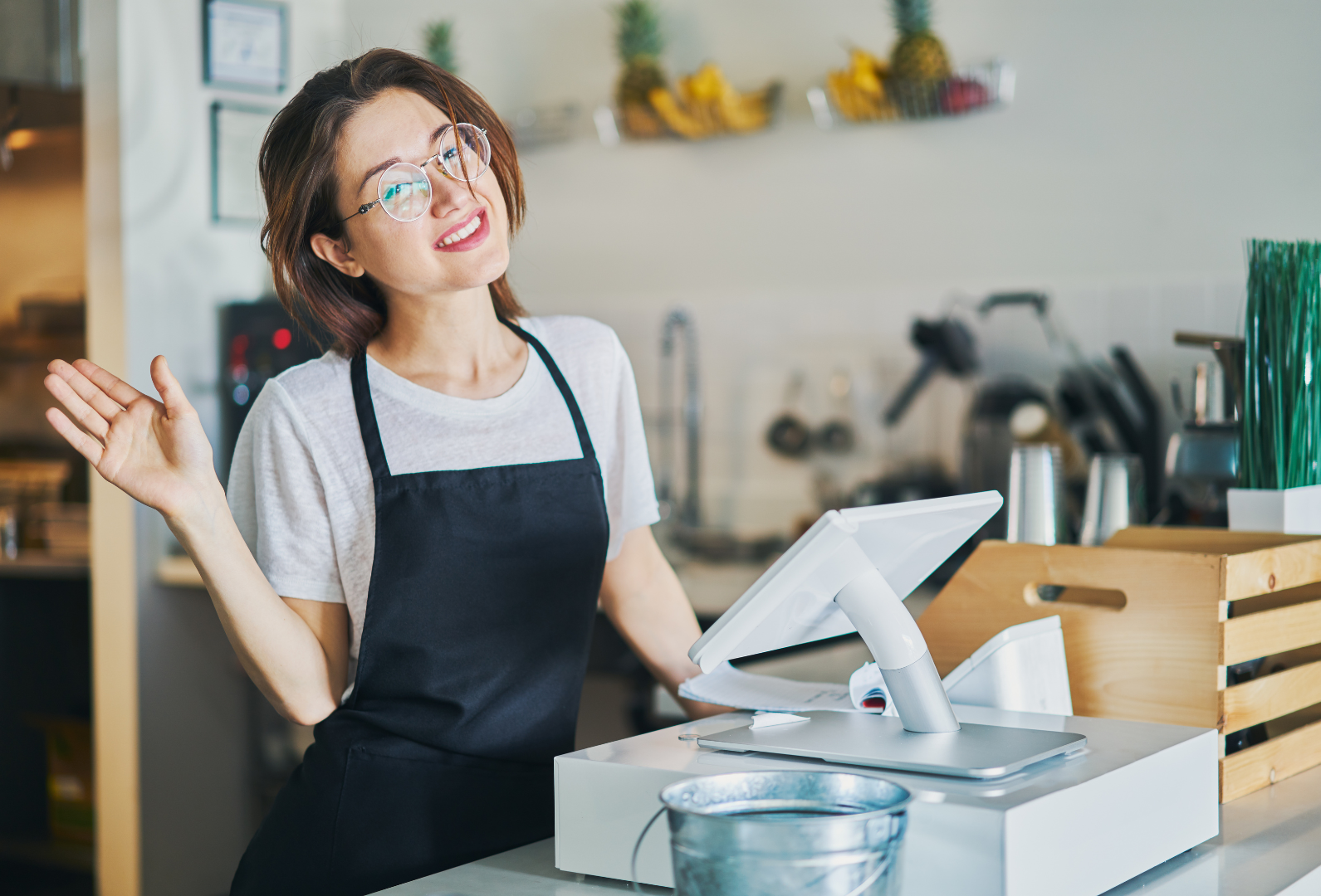 A woman in an apron is standing behind a counter in a restaurant.