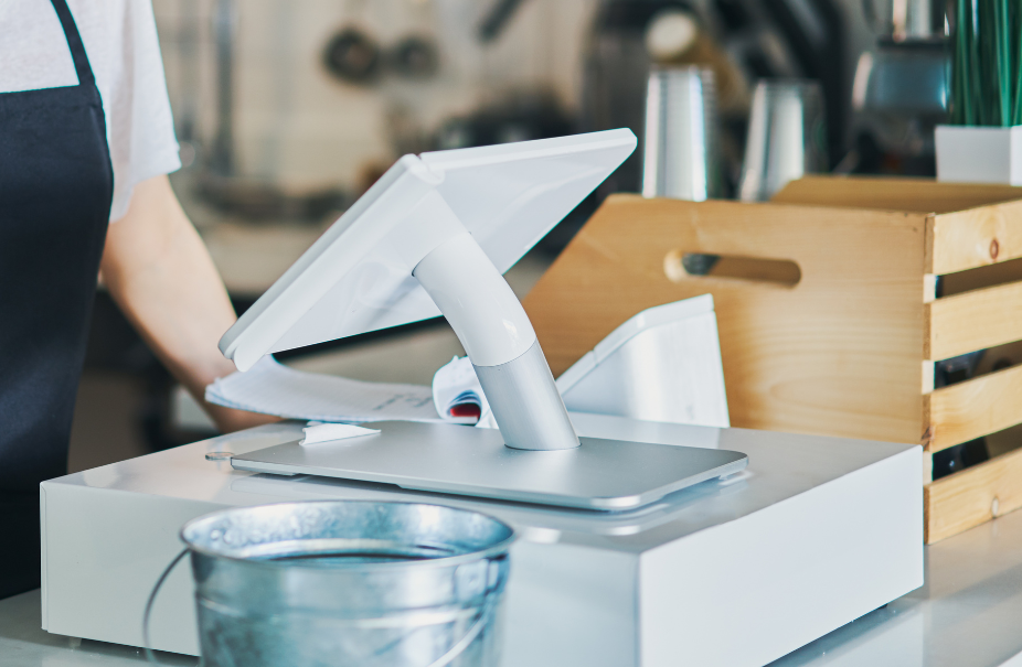 A person is standing behind a counter with a computer on it.