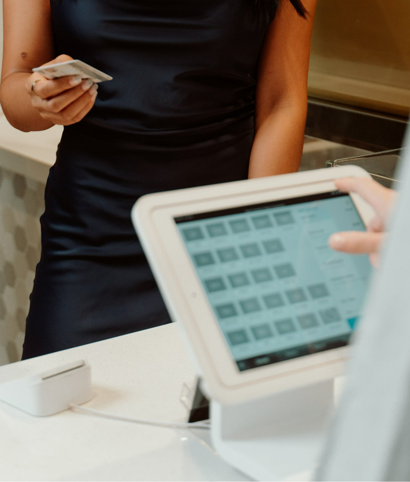 A woman in a blue dress is paying for something with a tablet