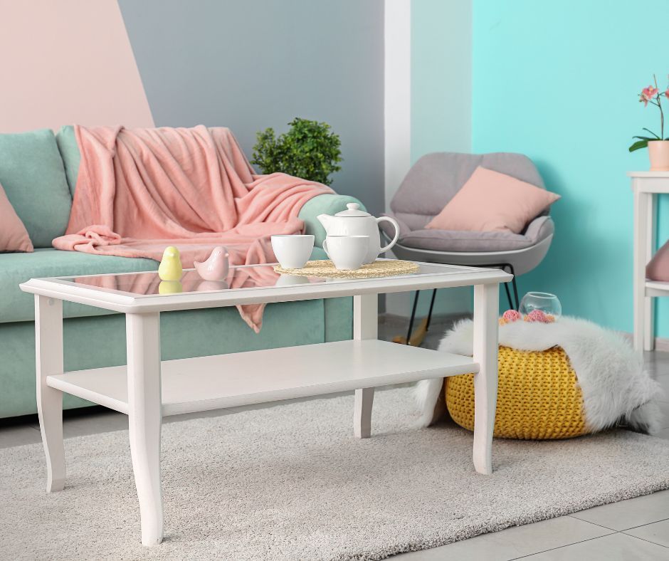A living room featuring a mint sofa with a pink throw, a white coffee table, and a gray chair against color-blocked walls.