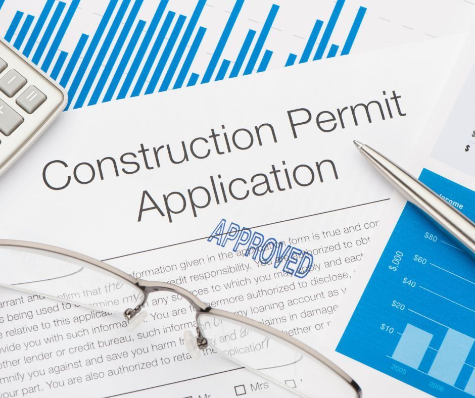 Construction permit application form with blue charts, glasses, pen, and approved stamp