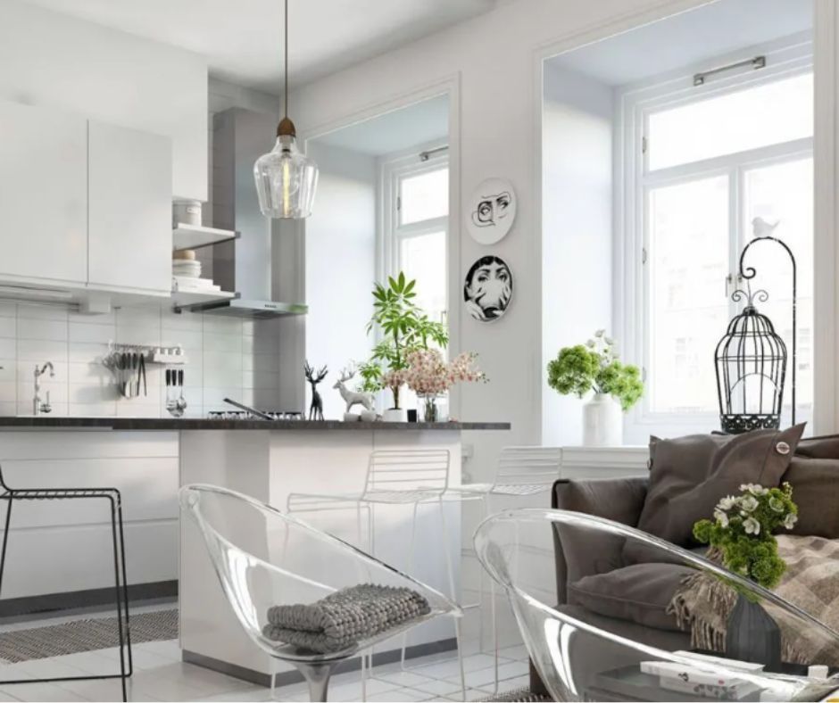 Modern kitchen with white cabinets, a breakfast bar, transparent chairs, and a cozy living area with a dark sofa.