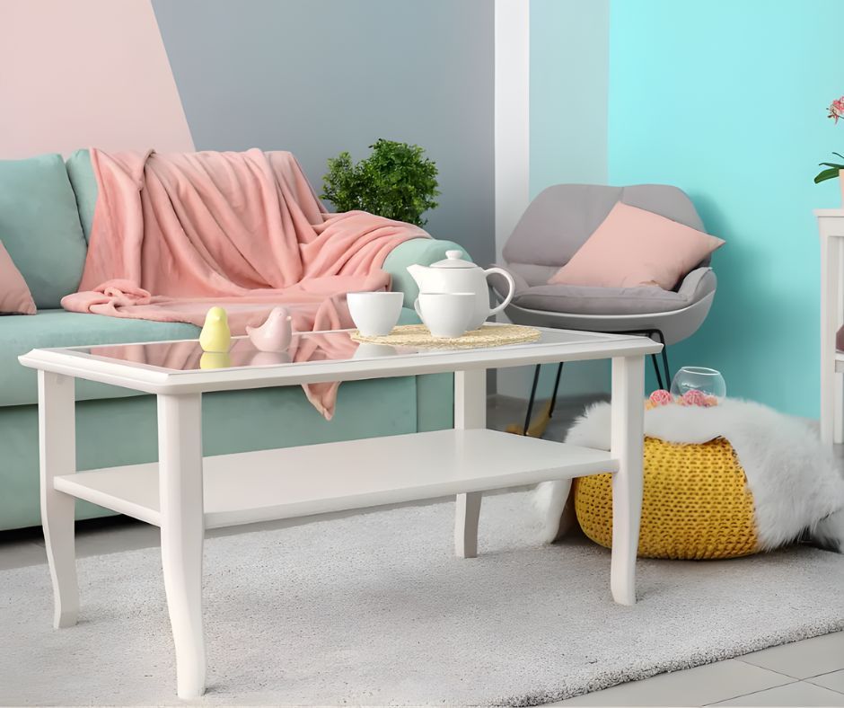 A living room featuring a mint green sofa with a pink throw, a white coffee table, a grey armchair, and a yellow pouf.