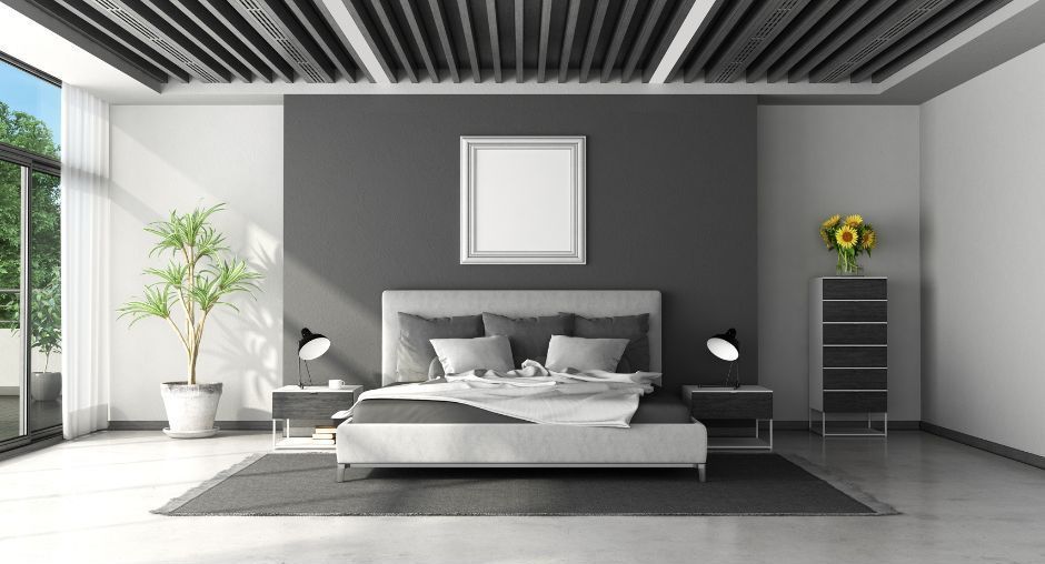 A modern, minimalist bedroom features a gray accent wall, a platform bed with neutral bedding, and a large window.