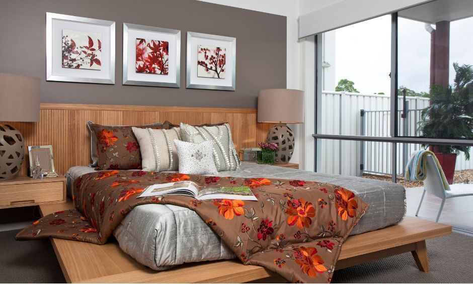 A platform bed with floral bedding and neutral pillows, set against a dark accent wall with three matching framed prints.