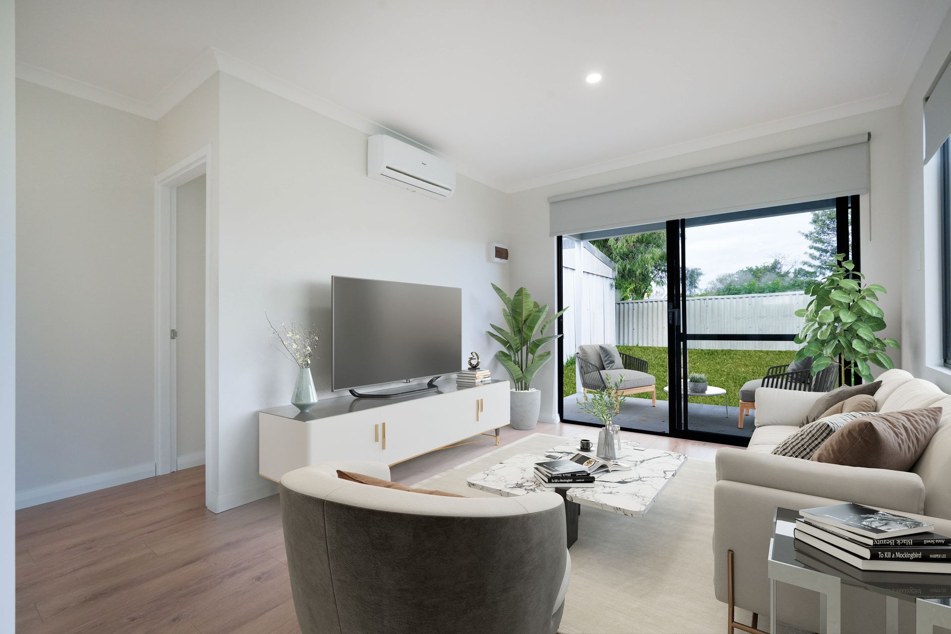 A modern living room with a TV, white media console, sofa, armchair, coffee table, and a sliding door to a backyard.