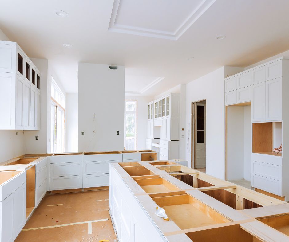 A kitchen under construction featuring white unfinished cabinetry, wood-framed countertops, and blank walls.